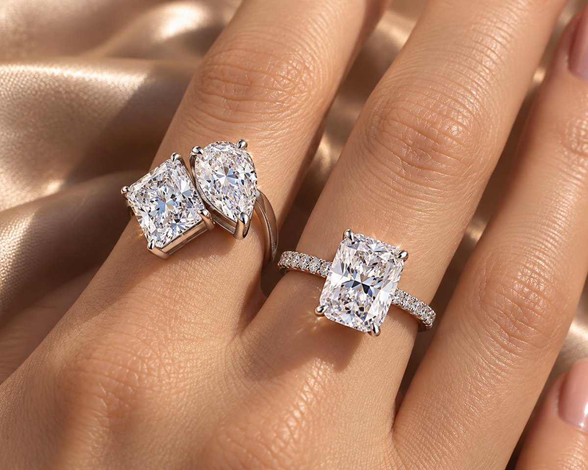Close-up of statement radiant and two-stone rings worn on a relaxed hand